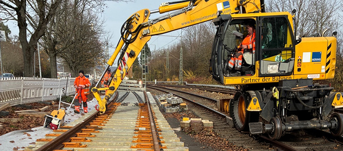 Zweiwegebagger und Mitarbeiter bei der Weichenmontage